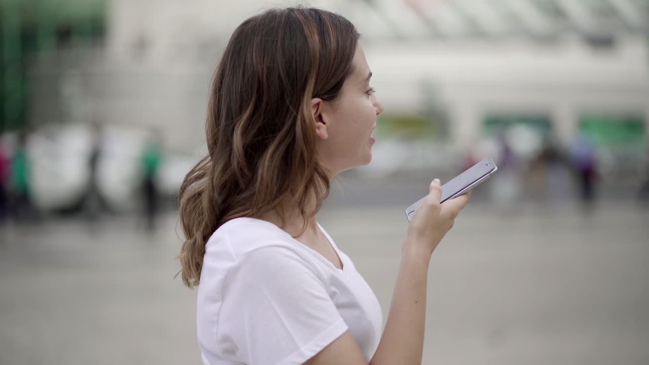 아름다운 미소 짓는 여성이 오디오 메시지를 녹음하고 있습니다.