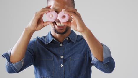 Video-of-biracial-man-holding-donuts-over-white-background