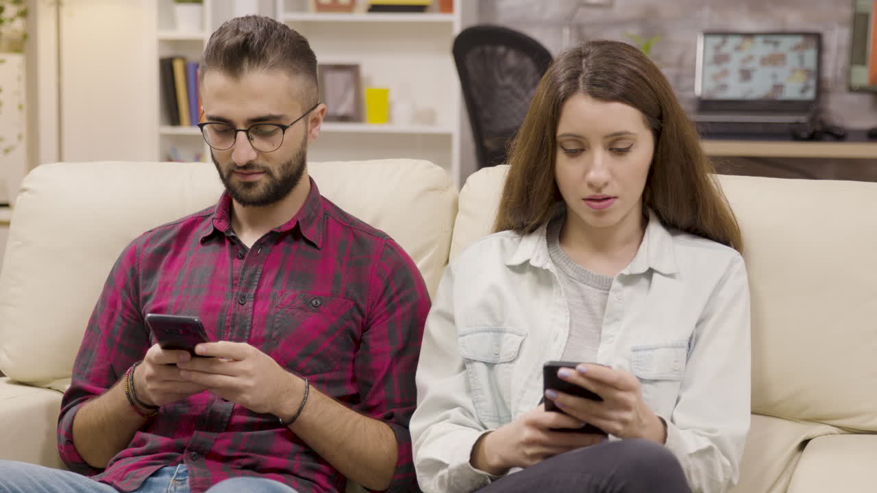 Couple using mobile phones at home