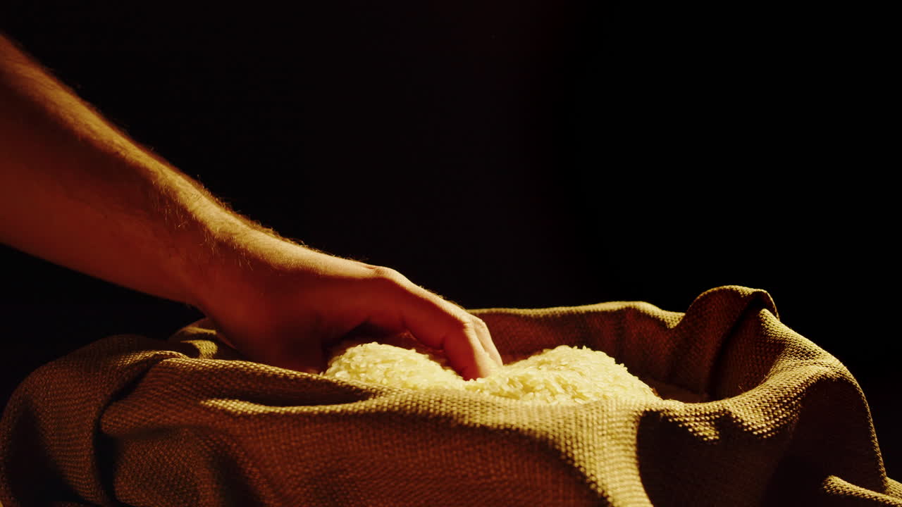 Hand Pouring Rice Grains into a Burlap Sack