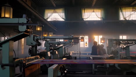 textile factory with weaving machinery and workers at sunset