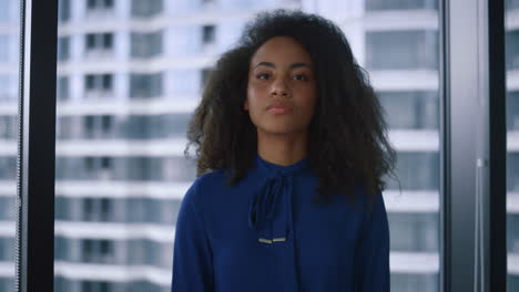 Serious-african-american-woman-looking-camera-in-business-centre-window-office.