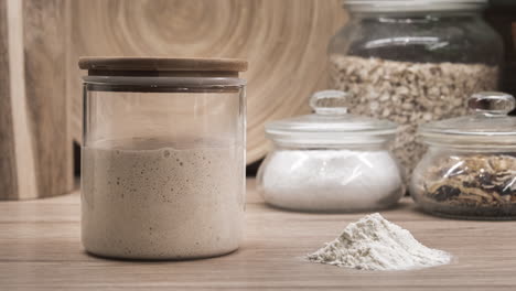 bubbly sourdough starter proofing in a glass jar at the kitchen - zoom-out shot, timelapse