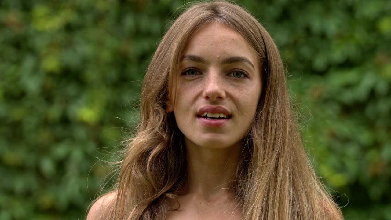 따뜻한 여름날 공원에서 매력적인 젊은 여성이 비누방울을 불며 놀고 있습니다.