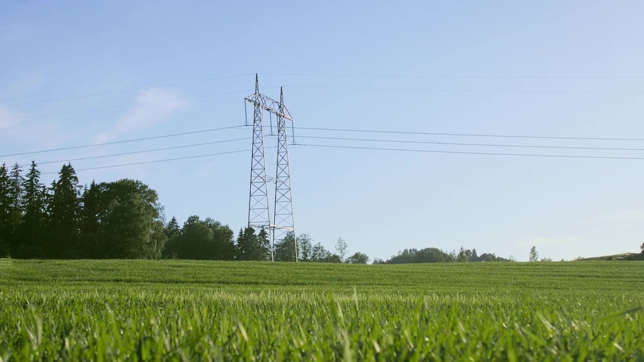 Gliding shot of a lone power line tower in an agricultural field. Captured near Oslo, Norway.