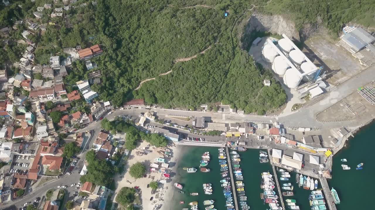 Drone flies above Arraial do Cabo port and tilts up to reveal the beautiful landscape in the distance