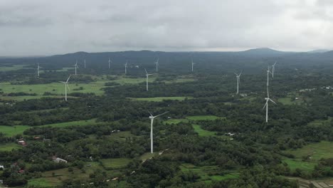 Eine-Malerische-Szene,-In-Der-Sich-Windmühlen-Anmutig-Gegen-Den-Himmel-Drehen,-Eingebettet-Zwischen-Charmanten-Häusern-In-Einer-Ruhigen-Ländlichen-Landschaft