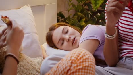 chicas adolescentes comiendo pizza y relajándose en la cama
