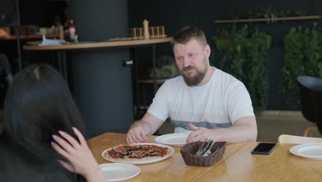 una pareja comiendo pizza en un restaurante.