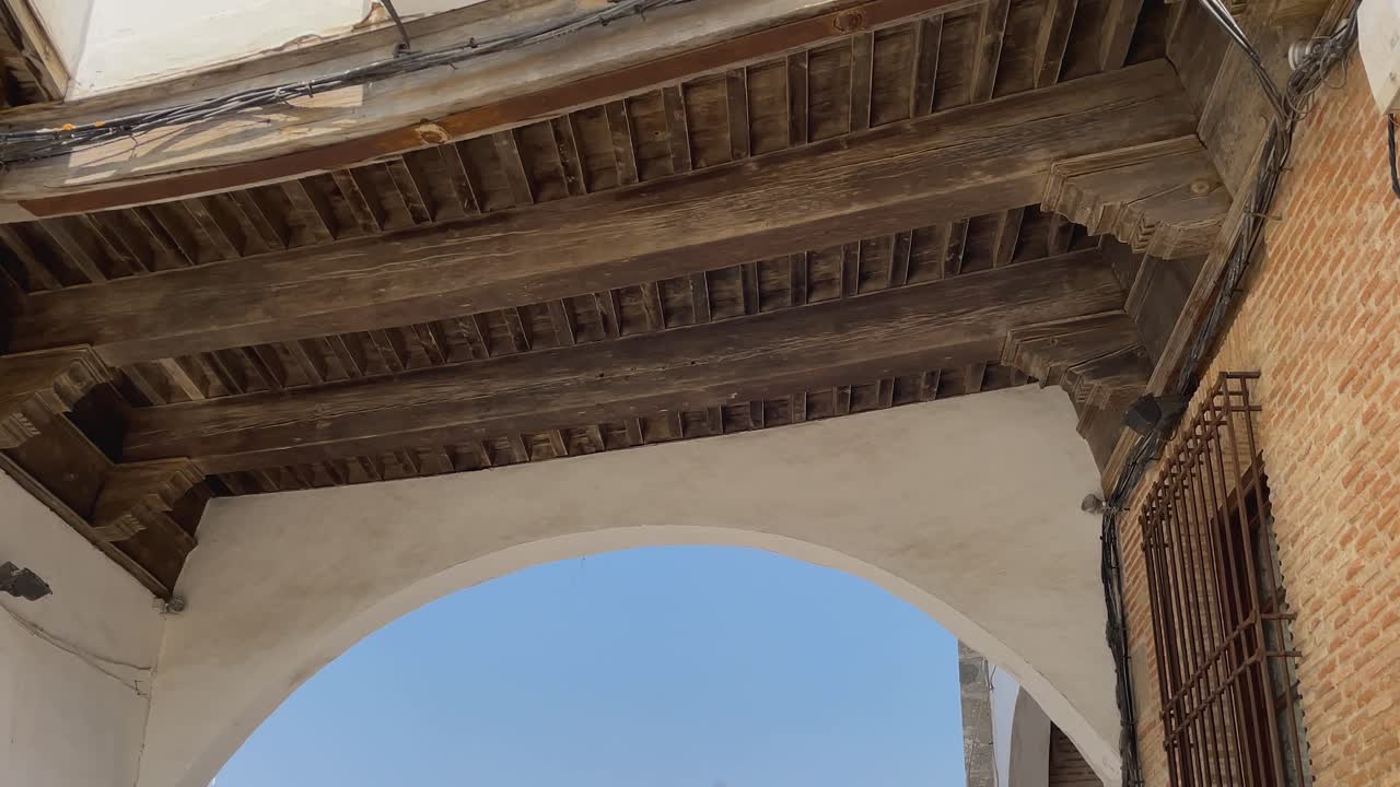 Slow-motion descending shot revealing the archway and traditional Castilian architecture in La Puebla de Montalbán, Toledo. Brick, stone, and wood elements reflect Spain’s rich architectural heritage