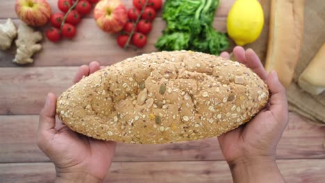 hand holding wheat brown baked bread on table