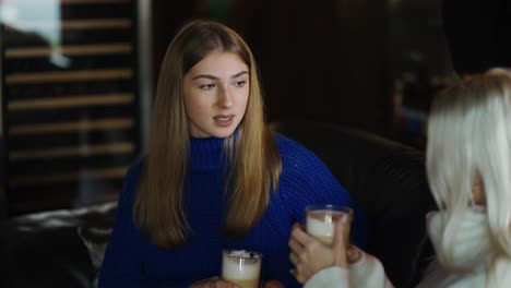 Two-women-on-sofa-are-having-a-relaxed-conversation-and-drinking-cappuccino