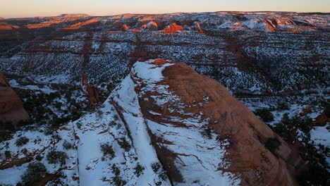 Drone-shot-hovering-over-snowy-covered-red-rock-formation