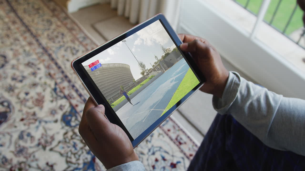 compuesto de un hombre sentado en casa, viendo el evento de jabalina de atletismo en la tableta