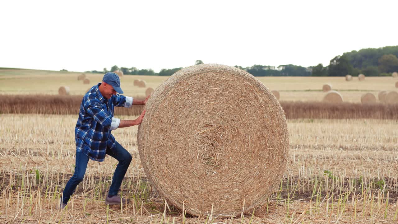 granjero sonriente rodando balas de heno y gesticulando en la granja 4