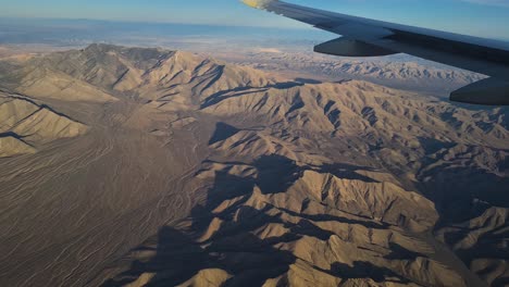 airplane flying above desert landscape, passenger pov over aircraft wing