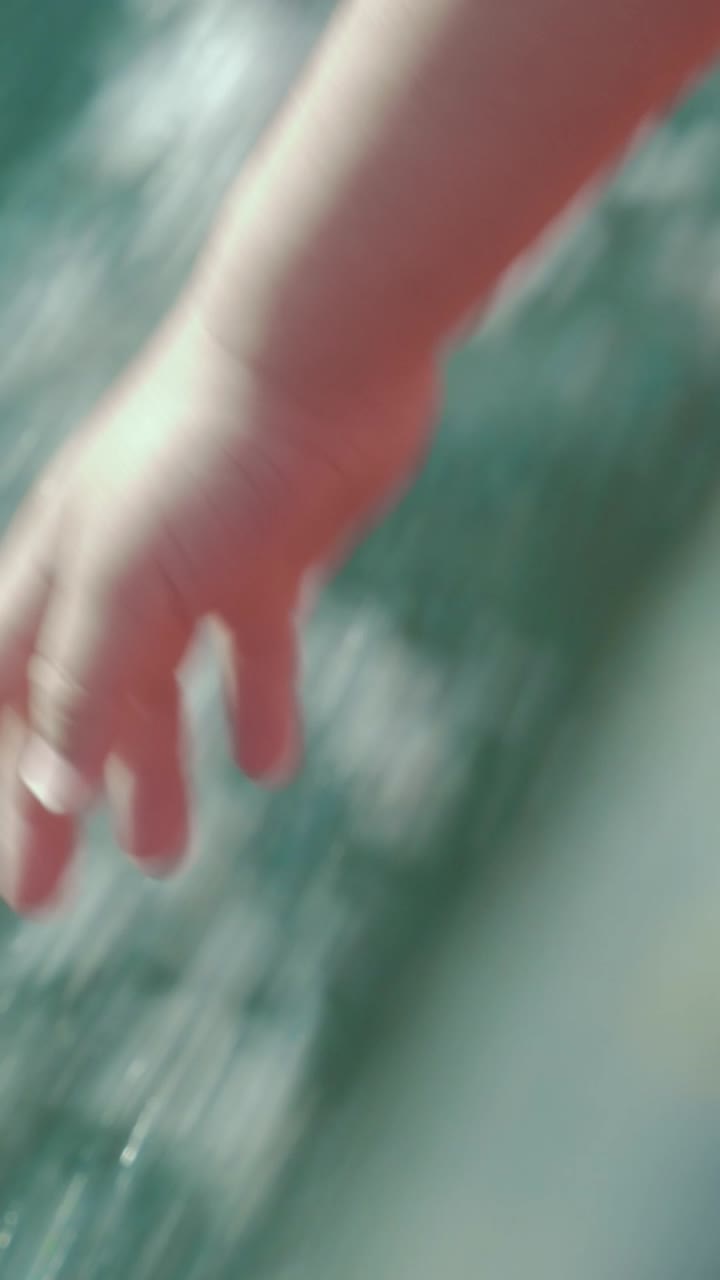 Close-up of Child's Hand Gently Touching Moving Water