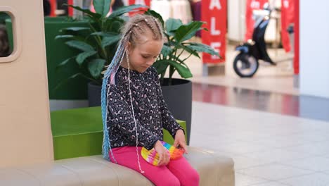 girl with african braids playing with pop it toy