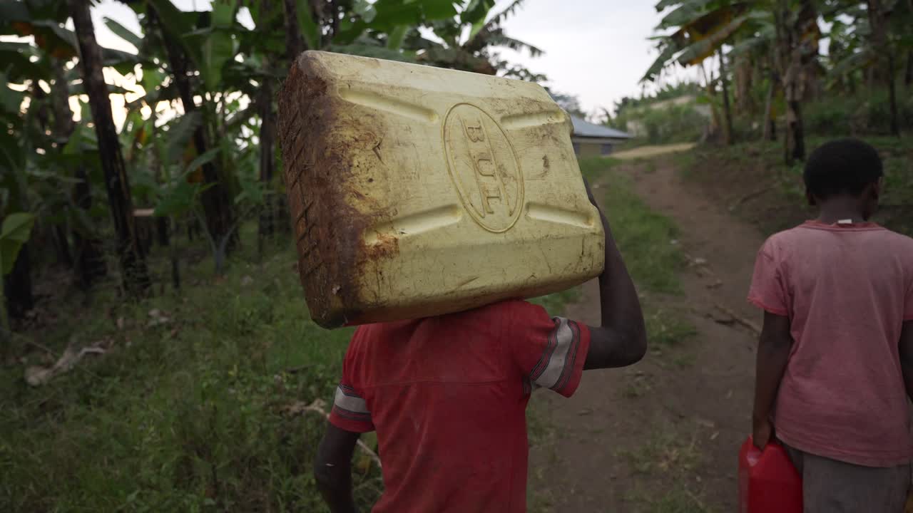 Two African children carrying water cans in Africa