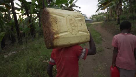 two african children carrying water cans in africa