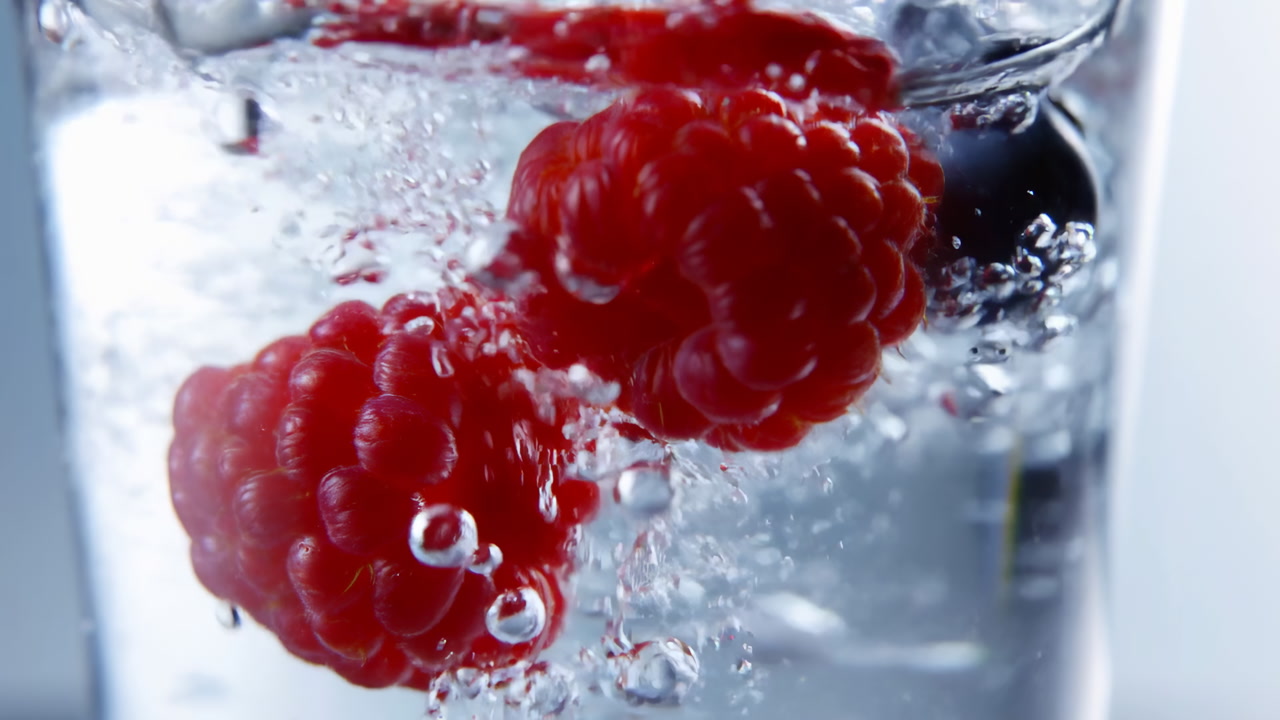 Raspberries And Blueberry Splashing In Glass Sparkling Water Macro Closeup Revealing Vibrant Red Raspberries