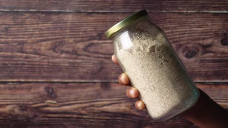 Hand-hold-a-glass-jar-of-a-almond-powder-,