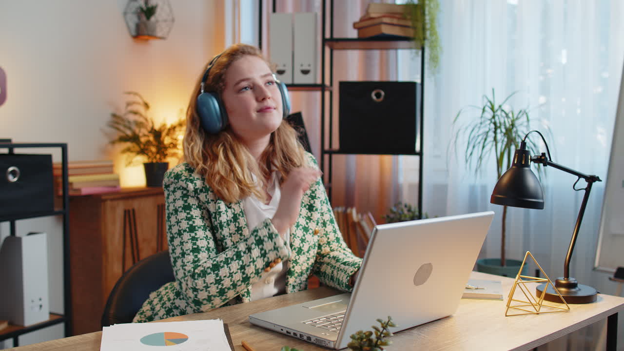 Businesswoman listening music through wireless headphones relaxing taking a break, laptop on table