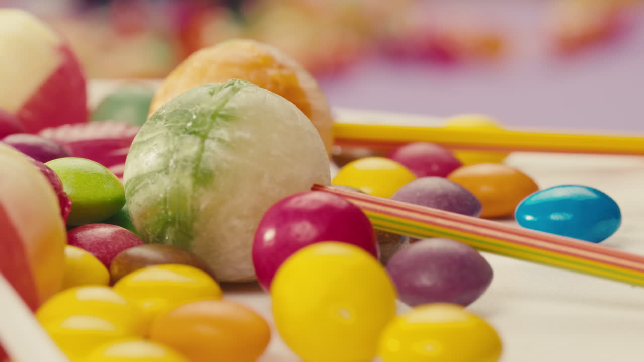 Colorful dragee candies, lollipops, bonbons on white background, move in circle, side view close-up. Summer bright texture studio shot for store, supermarket. Mix of children's sweets made of sugar.