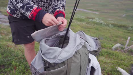 hiker organizing his things on the backpack - man packing his bag