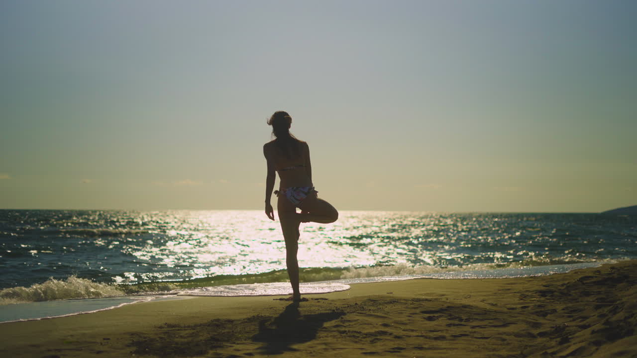 해가 지는 해변에서 요가를 연습하는 여자