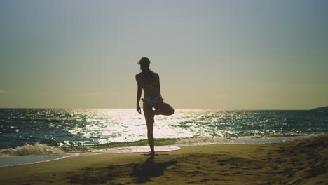 woman practicing yoga on a beach at sunset