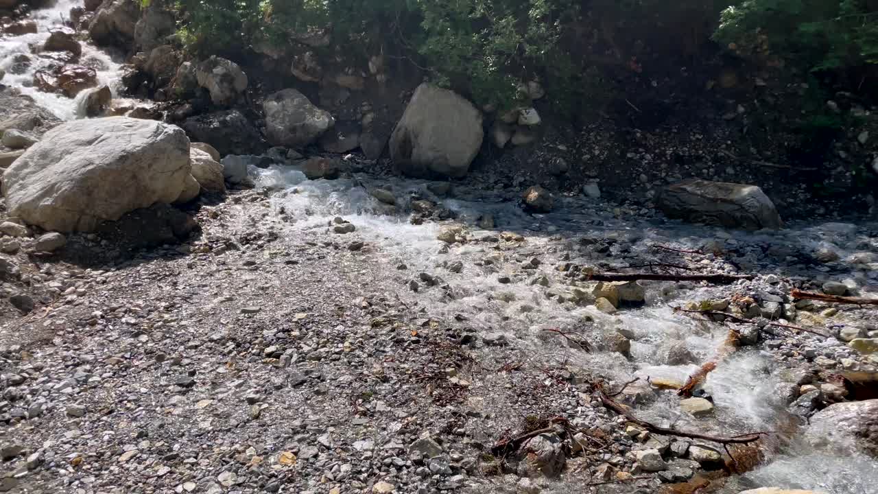 pequeña cascada idílica que fluye por las montañas rocosas en verano - toma panorámica a cámara lenta