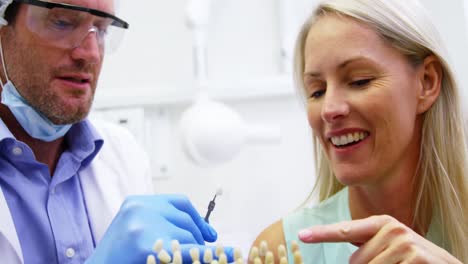 dentist showing teeth shades to female patient