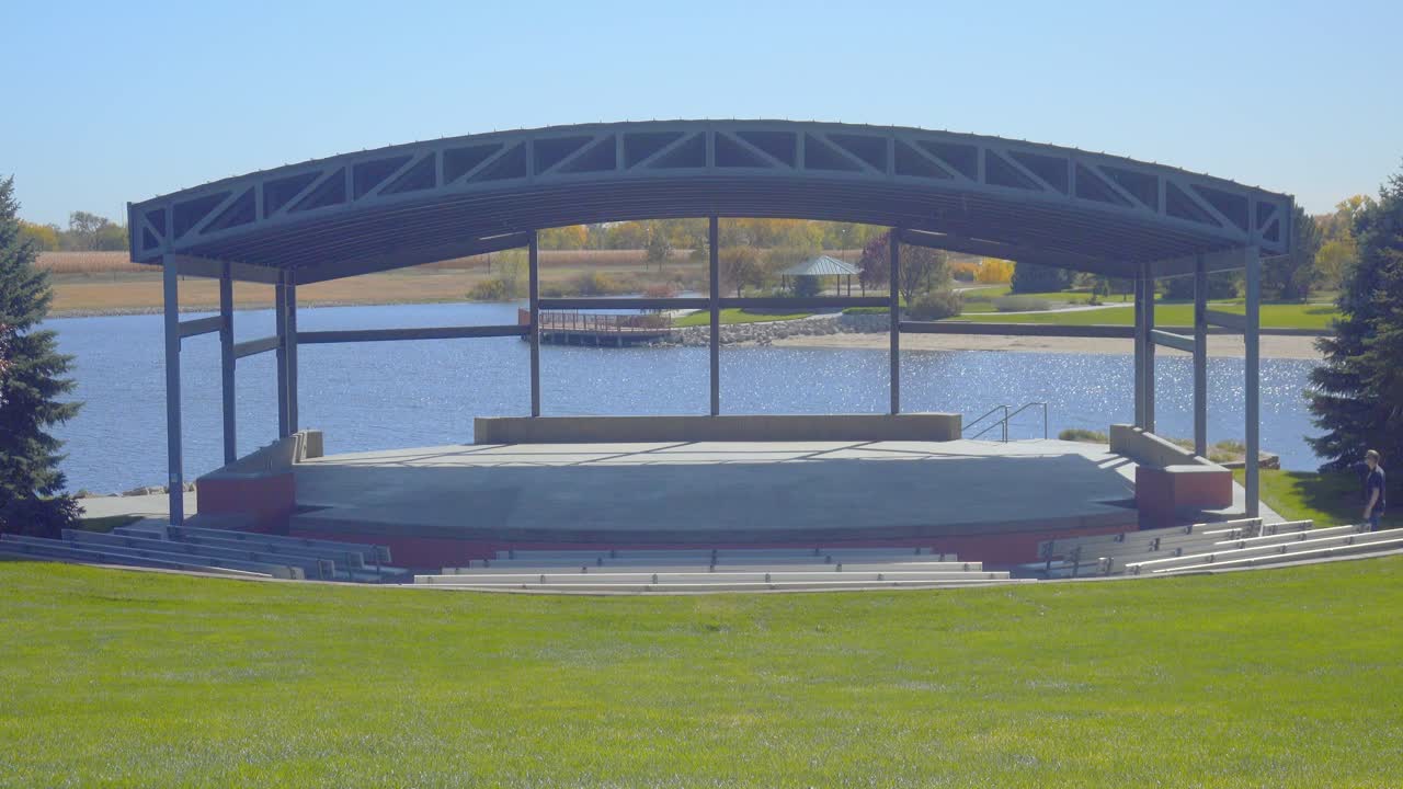 한 남자 가 아름다운  ⁇ 빛 날 에 야외 공원 암피테아터 에서 비어 있는 무대 로 걸어가고 있다