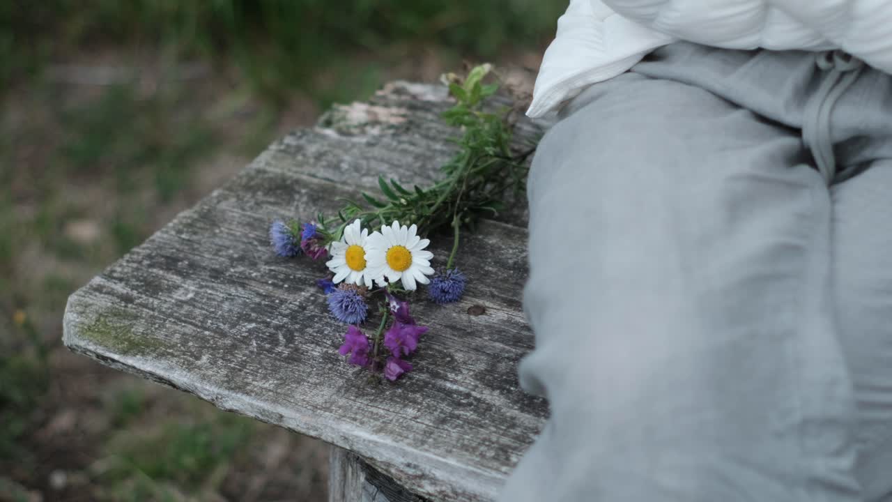 Kronieken van Liefdesverdriet: Vrouw vindt troost op een bankje, een symbolisch boeket neerleggend