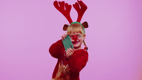 Toddler-girl-in-Christmas-deer-antlers-enthusiastically-playing-racing-video-games-on-mobile-phone