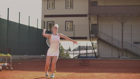 una chica bonita juega al tenis. una mujer con un traje de entrenamiento blanco entrena profesionalmente al tenis.
