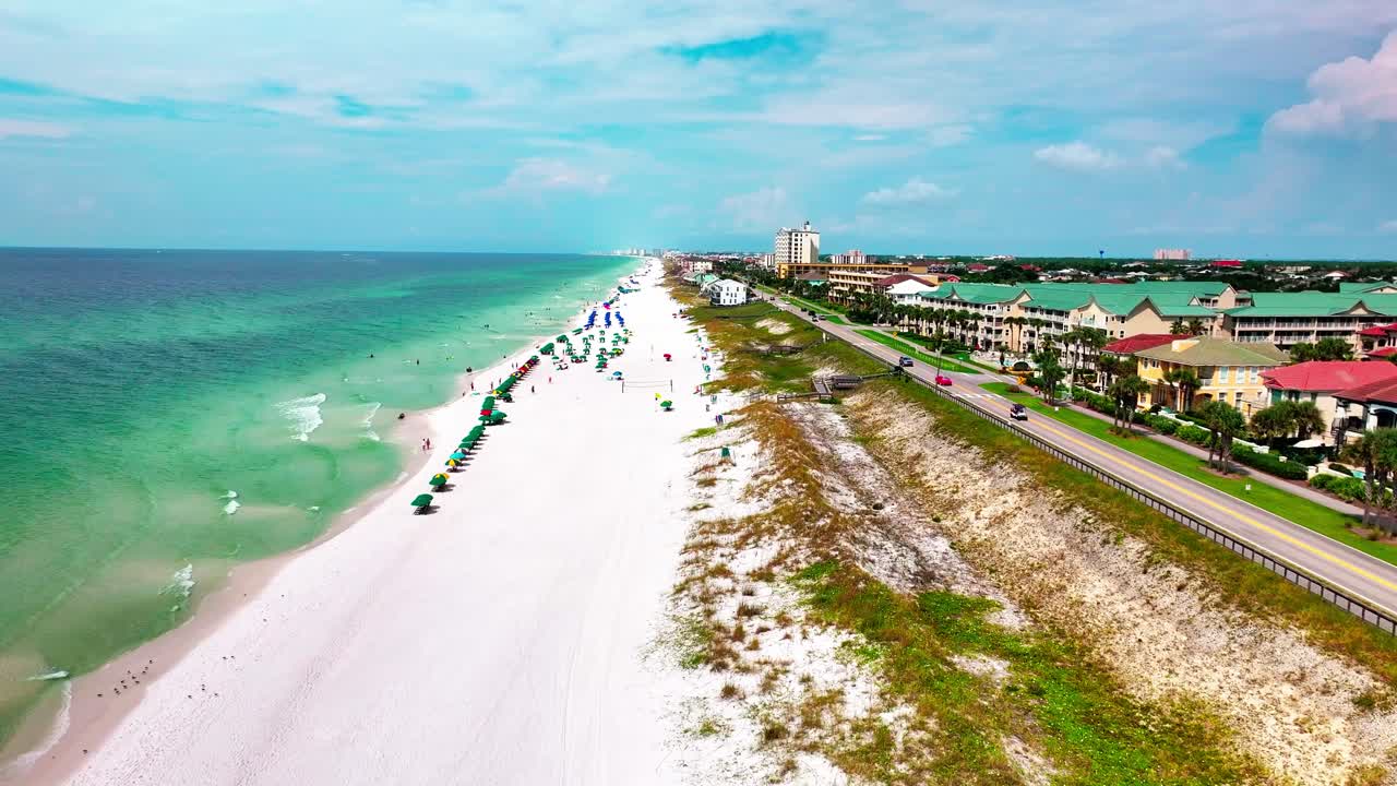 Ripresa con drone che sorvola la spiaggia di sabbia bianca di Destin, Florida, con una vista del Golfo del Messico sulla sinistra e avena di mare e la vecchia autostrada 98 sulla destra