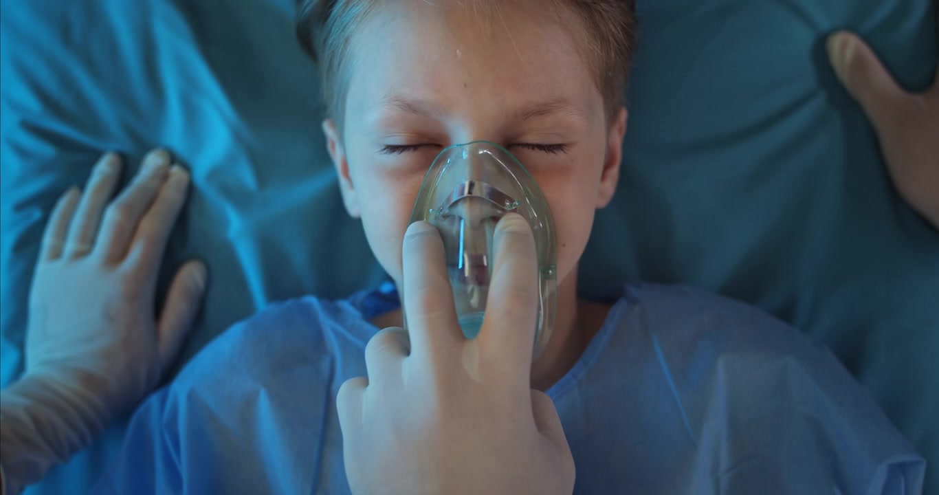 Professionista medico rimuove la maschera per l'ossigeno da un giovane paziente bambino