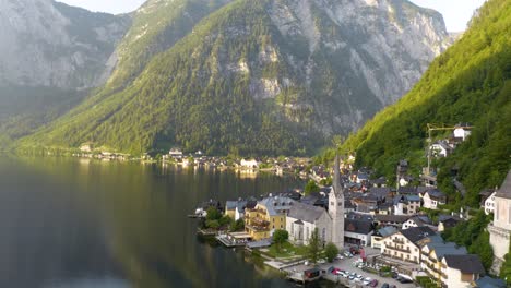 Drone-Flying-Away-from-Hallstatt-above-Lake-surrounded-by-Mountains