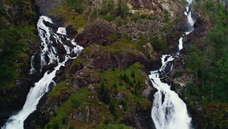aerial rising crane shot of twin falls of låtefossen at dusk
