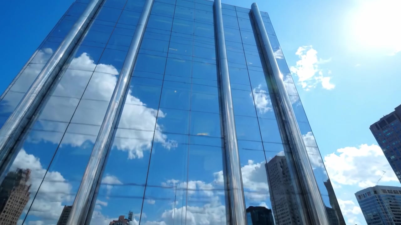 Edifício Bancário Urbano Moderno Apresentando Fachada de Vidro Refletivo e Céu Azul Brilhante, Exibindo Design Arquitetônico em um Ambiente Urbano Vibrante.