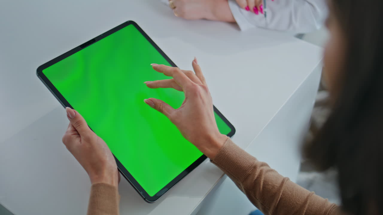 Woman using a tablet with green screen in office