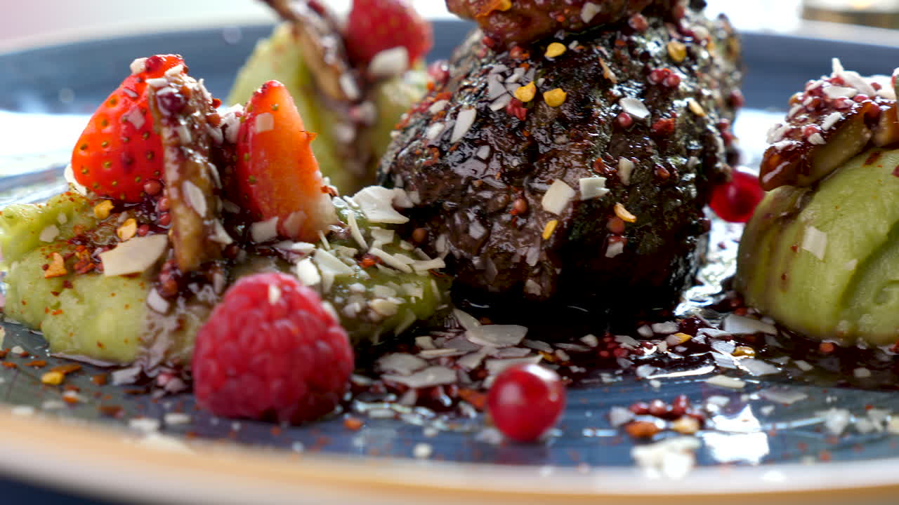 A gourmet food dish with steak, fruit and sauce