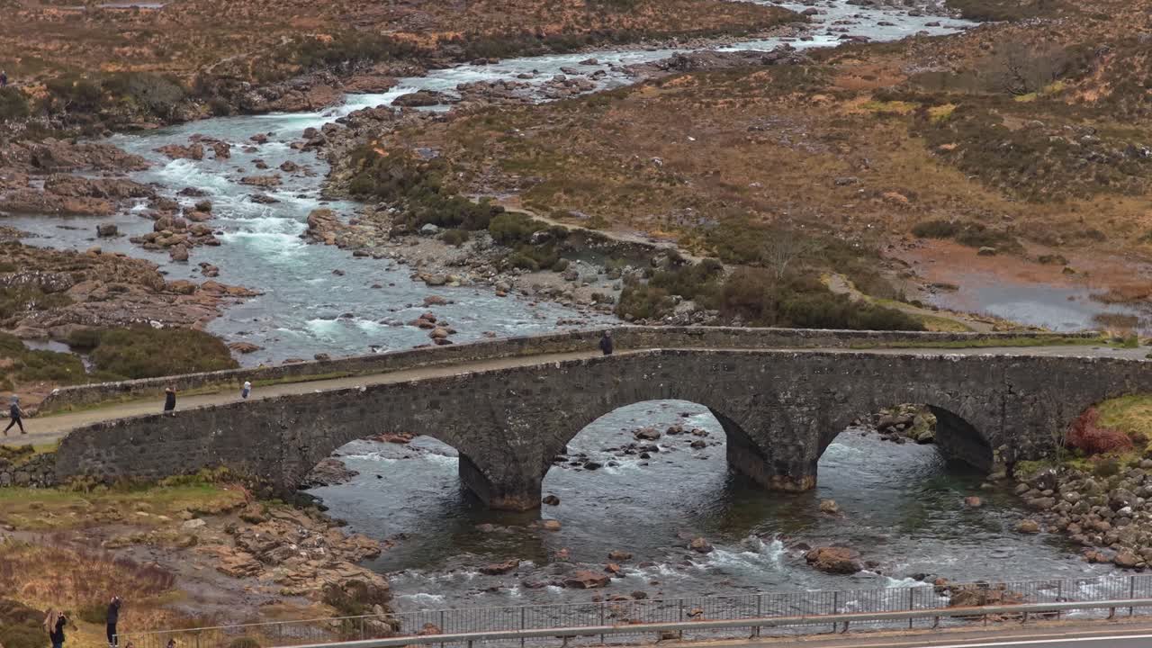 Tourists walking on the sligachan old bridge in scotland