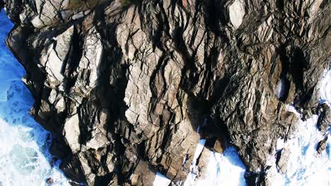 Aerial-Drone-Shot-in-Slow-Motion-Over-Slated-Rocks-Along-Cornish-Coastline-with-White-Ocean-Waves