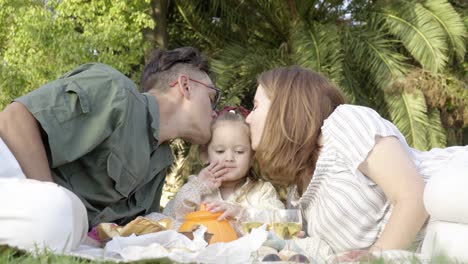 a happy young family picnicking with their cheerful daughter in the city park