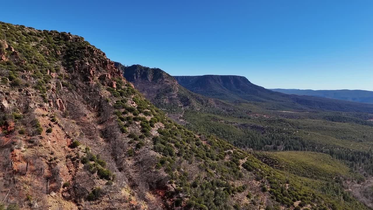 Close up View of Mountains, Aerial view, push in shot, Mogollon Rim in Payson Arizona, covered in trees, early summer, blue skies and jagged edges
