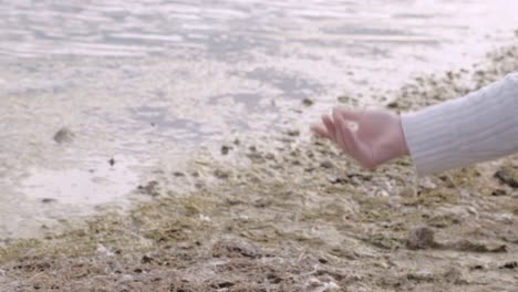 mujer despreocupada relajándose lanzando una pelota a la orilla del lago