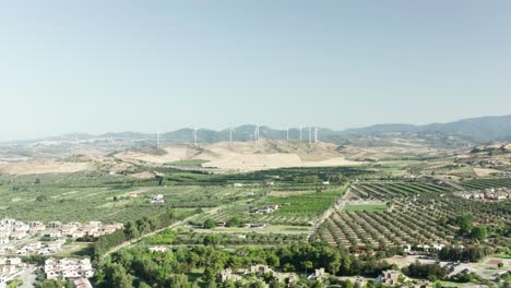 Vista-Aérea-Del-Interior-De-Calabria,-Campos-De-Olivos-Y-Turbinas-Eólicas-En-El-Fondo,-Calabria,-Italia